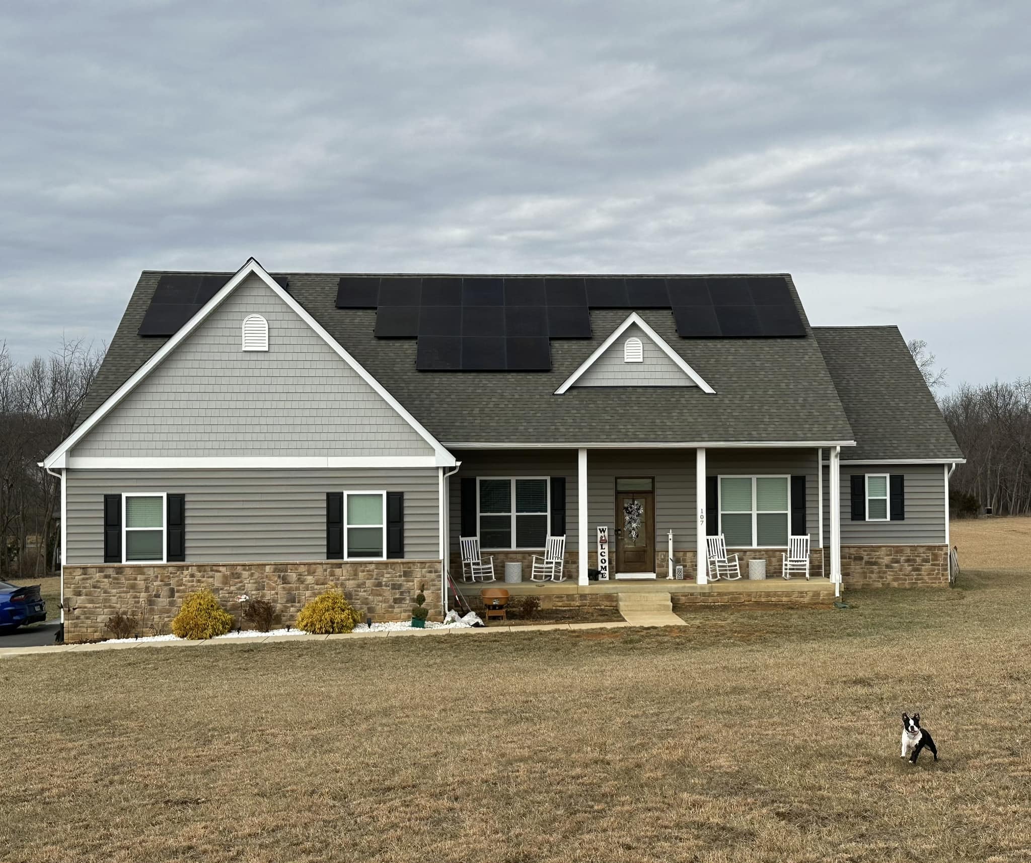 Single-story stone and siding home with solar panels installed in rural setting